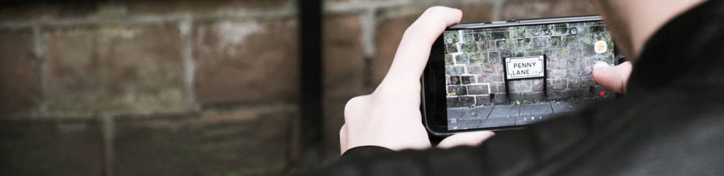 A tourist taking a picture of the Penny Lane sign in Liverpool.