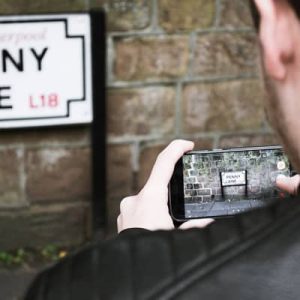 Photographer taking a shot of the Penny Lane sign in Liverpool