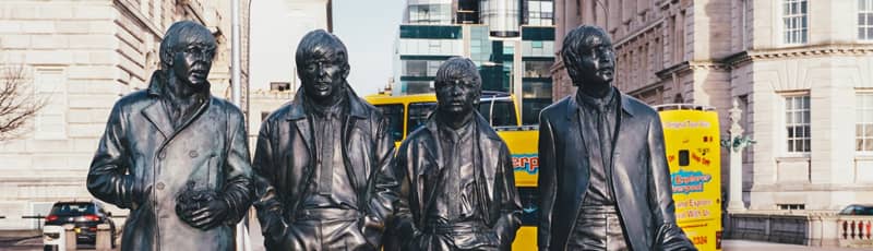 The Beatles statues in Liverpool with the City Explorer bus in the background.
