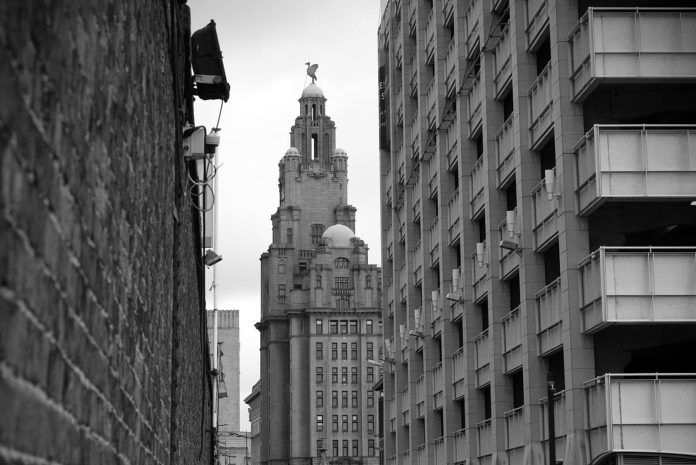 Black and white shot of buildings in Liverpool sandwiched between the Royal Liver Building.
